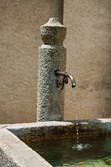 Close-up of stone fountain and spout with fresh water in a sunny day at Megeve. A famous ski resort located in the Haute-Savoie Province, near the Mont Blanc in the French Alps.