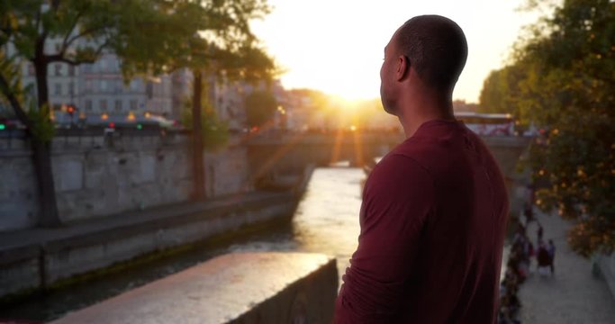 African-American male on vacation in Paris watch a beautiful sunset outside, Young man traveling in Paris, France watching the sun set near the Seine River, 4k