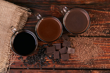 Glasses of chocolate milkshake on wooden table closeup, sweet dessert food 