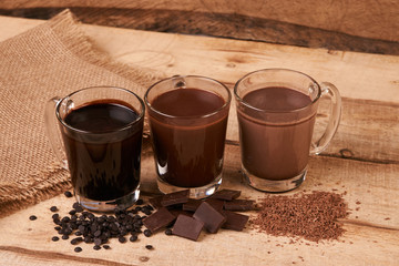 Glasses of chocolate milkshake on wooden table closeup, sweet dessert food 