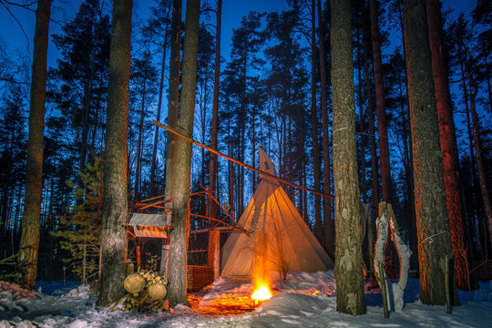 Tipe in the forest. The wigwam in the winter forest. Living in the forest. Night forest with a fire.