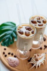 Two cups of ice coffee with coffee beans on wooden table, selective focus. summer delicious drink