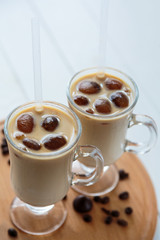 Two cups of ice coffee with coffee beans on wooden table, selective focus. summer delicious drink