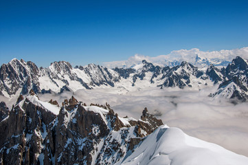 Snowy peaks and mountains in a sunny day, viewed from the Aiguille du Midi, near Chamonix. A famous ski resort located in Haute-Savoie Province, at the foot of Mont Blanc in the French Alps.