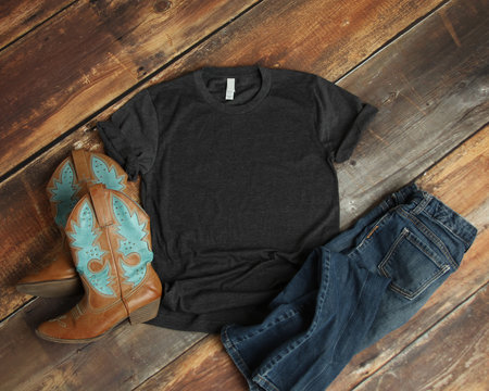 Mockup of blank gray tshirt on rustic wood background with cowboy boots and jeans