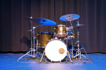 Fototapeta na wymiar Classic professional basic drum kit set on a stage with black curtains in the background.