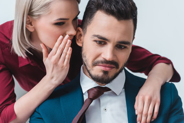 businesswoman whispering something to handsome young businessman at workplace