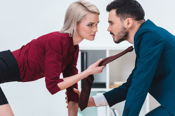 Fototapeta premium sexy young couple of business people looking at each other in foreplay at workplace