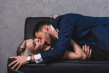 Obraz premium side view of sexy young couple kissing on couch