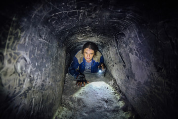 Man explores narrow passage in ancient abandoned underground chalky cave monastery