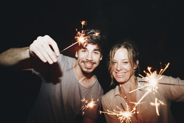Caucasian man and woman couple playing with sparklers celebration and festive party concept