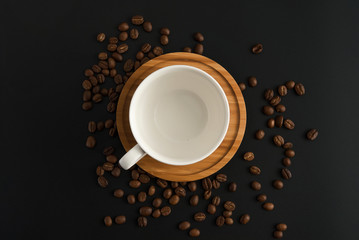 Obraz na płótnie Canvas Coffee cup with wooden plate, roasted coffee beans on black background.