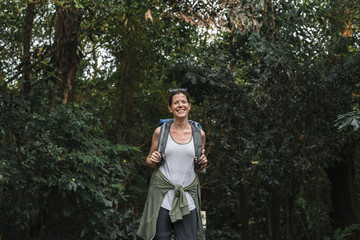 Cheerful female backpacker in the forest