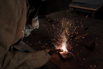 cropped image of worker in protection mask welding metal at factory