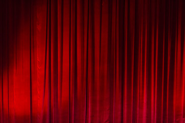 Large red curtain with spot light and fading into dark.