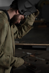 Obraz premium side view of welder lifting up protective mask to look at his work