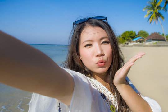 self portrait of gorgeous beautiful and happy Asian Korean or Chinese woman 20s taking selfie photo sending kiss with mobile phone camera