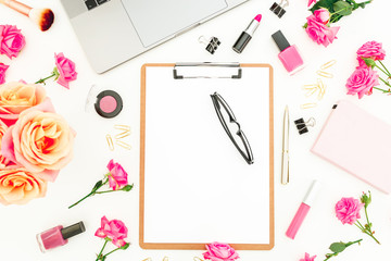 Laptop, clipboard, roses flowers, cosmetics and accessories on white background. Flat lay. Top view. Freelancer office or blogger concept