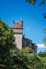 Partial view of Castle of Menthon-Saint-Bernard with trees and blue sky, near the Lake of Annecy. Department of Haute-Savoie, Auvergne-Rhone-Alpes region, southeastern France.