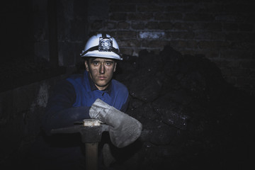 a miner with a pick sitting on the corner all tired and dirty from the coal dust after a hard work...