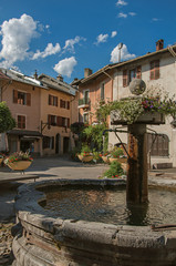 Fototapeta na wymiar Square with stone buildings, fountain and blue sunny sky in Conflans. An historical hamlet near Albertville. Located at the department of Haute-Savoie, southeastern France.