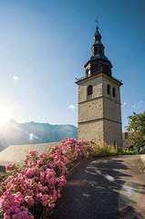 View of church steeple and colorful flowers in Conflans. An historical hamlet near Albertville. Located at the department of Haute-Savoie, southeastern France. Retouched photo.