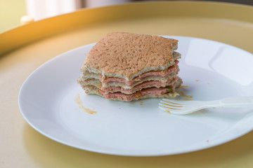 Bread lay with layer of ham on white dish.