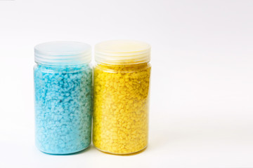 Two jars with small pebbles, yellow and turquoise.