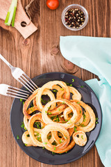 Fried onion rings in batter on a plate on a wooden table. Top view