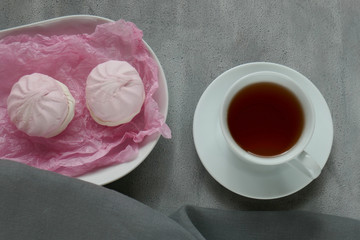 morning coffee . cup with coffee and pink marshmallow in a white oval dish on a gray background.  flat lay , top view,copy space