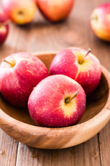 Red ripe apples in a wooden plate and on a wooden table