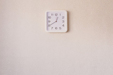 A Square white watches hang on an empty wall.