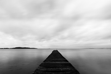 Long exposure first person view of a pier on a lake, with perfectly still water