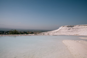 beautiful landscape with white rocks and calm water of pool in pamukkale, turkey