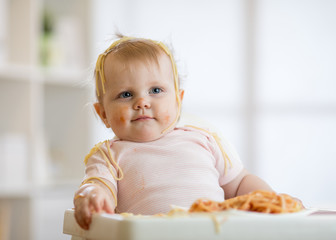 Cute baby girl eating her lunch and making a mess