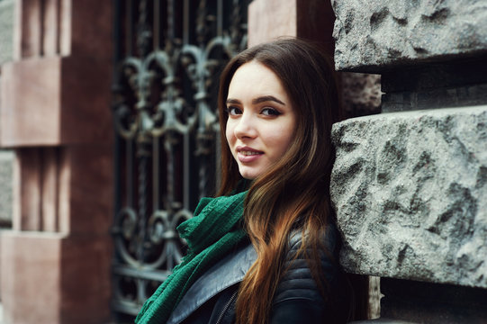 Portrait of a young woman on a city street . The girl in a fashionable leather jacket .