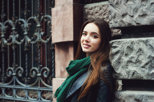 Portrait of a young woman on a city street . The girl in a fashionable leather jacket .