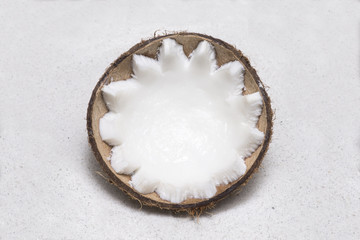 Half coconut lying in white sand