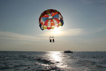 Fototapeta na wymiar A man and a girl are flying on a parachute.