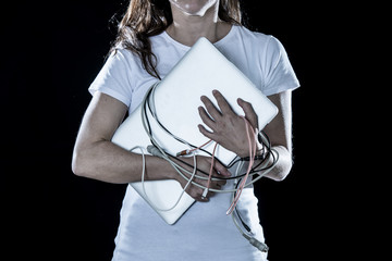 Closeup of an over worked woman holding a laptop and cables in computer addiction concept.