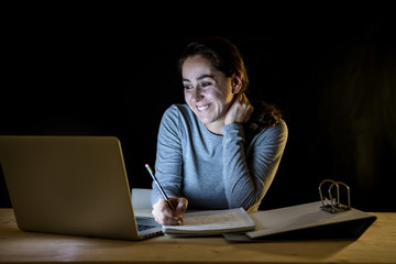 Overworked and tired student woman studying late at night on black background.