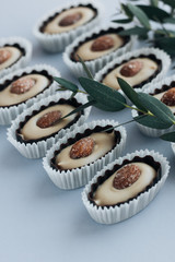 Composition of delicious praline sweets with almonds and green twigs on blue background