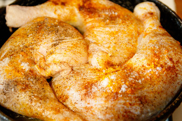 Raw chicken legs with spices on it. In a frying pan.