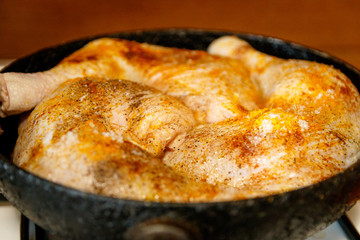 Raw chicken legs with spices on it. In a frying pan.