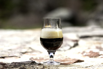 glass of stout beer with foam in nature