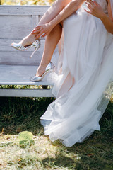 Bride's morning in the garden with vintage bench in the garden.. Fine art wedding. Portrait of a young beautiful sexy tender bride with red lips in white lace dress near the mirror. 