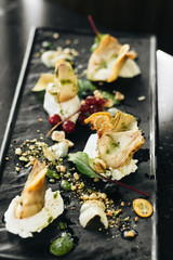Delicious cheese pieces and berries on stone slab