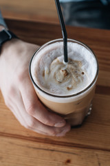 Glass of delicious cappuccino coffee on wooden table 