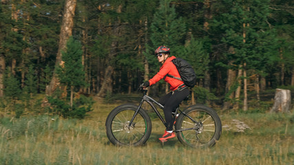 Fototapeta na wymiar Fat bike also called fatbike or fat-tire bike in summer riding in the forest. Beautiful girl and her bicycle in the forest. She rolls her bike and poses to the operator.