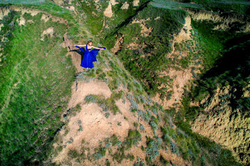 girl in a beautiful dress is standing on a cliff above a precipice. A girl in a blue dress is...